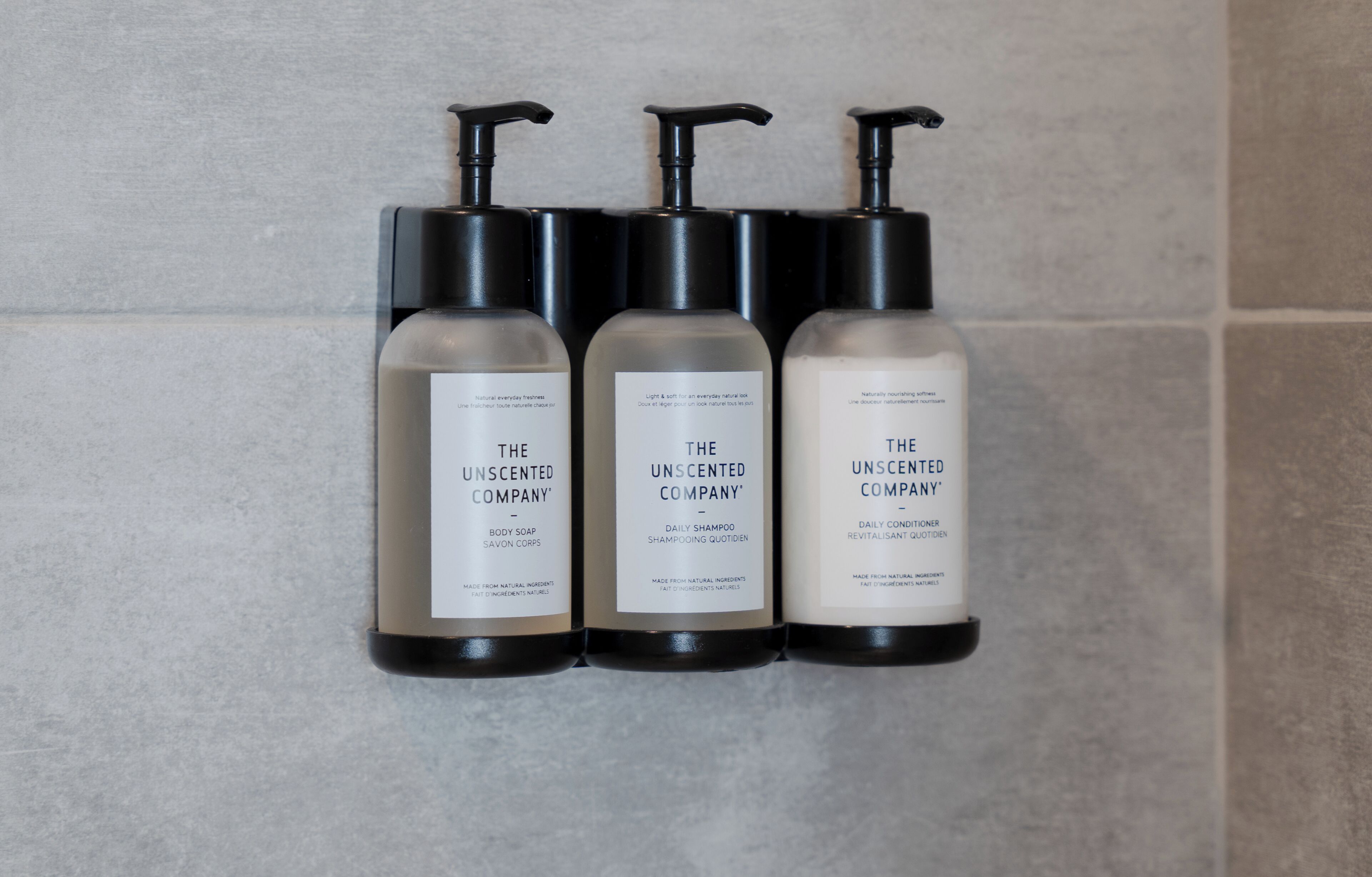 Three bottles of The Unscented Company body soap, daily shampoo, and daily conditioner.