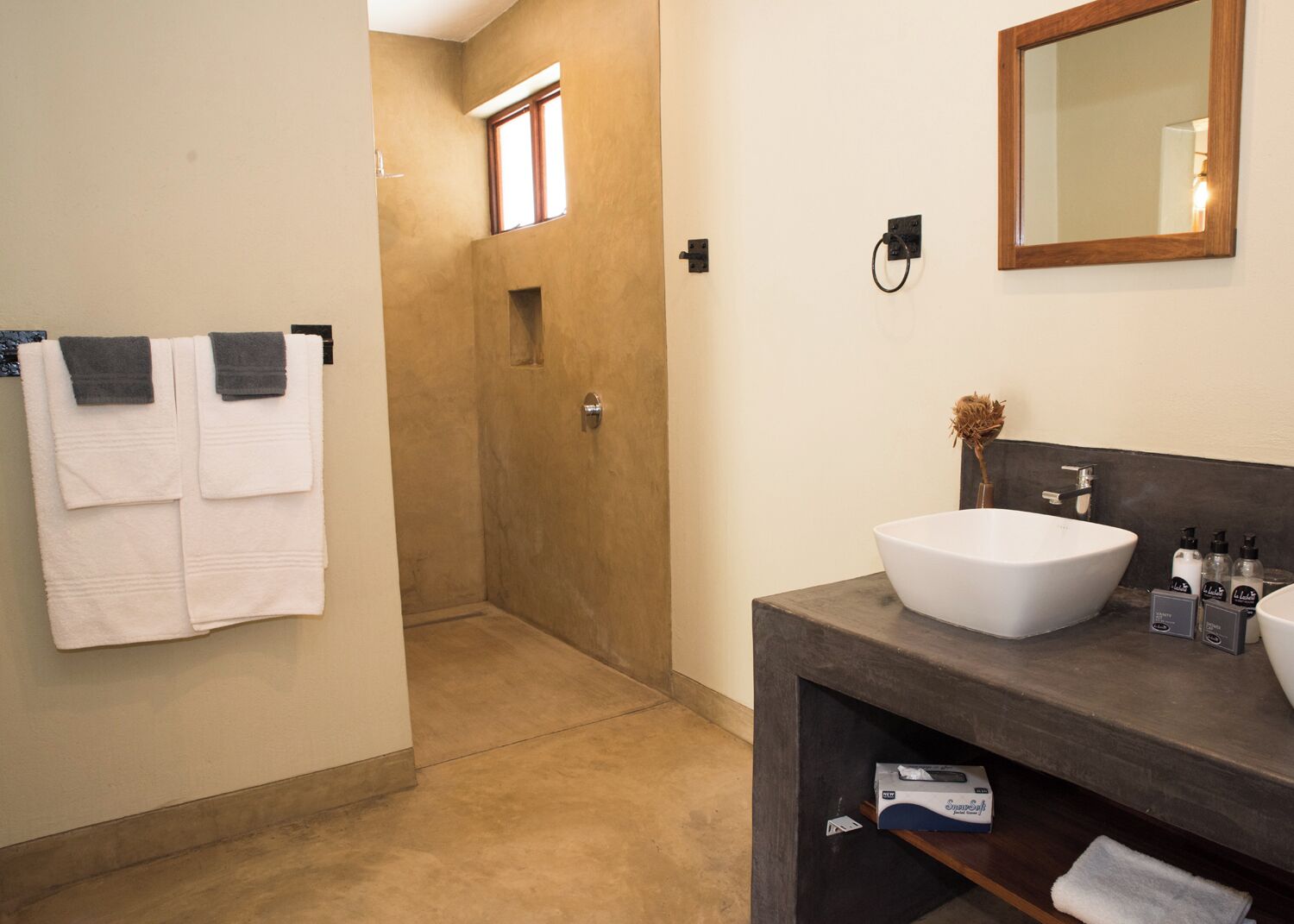 Een badkamer met een grote witte wasbak, een spiegel en twee handdoeken aan de muur.