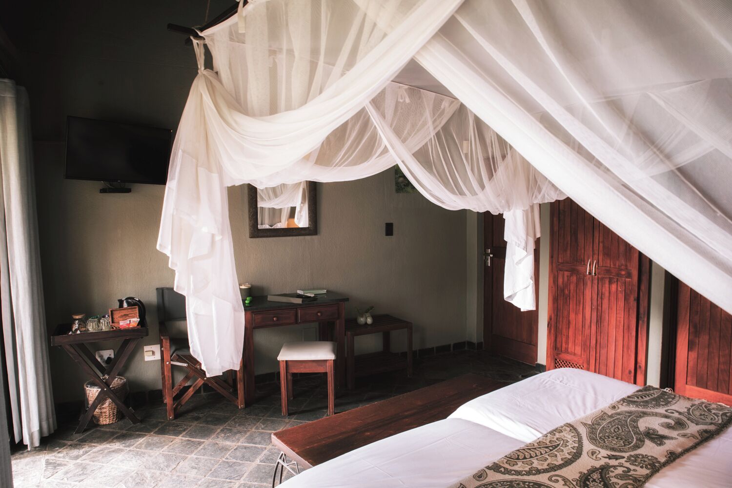 A bedroom with a bed, a desk, and a chair.