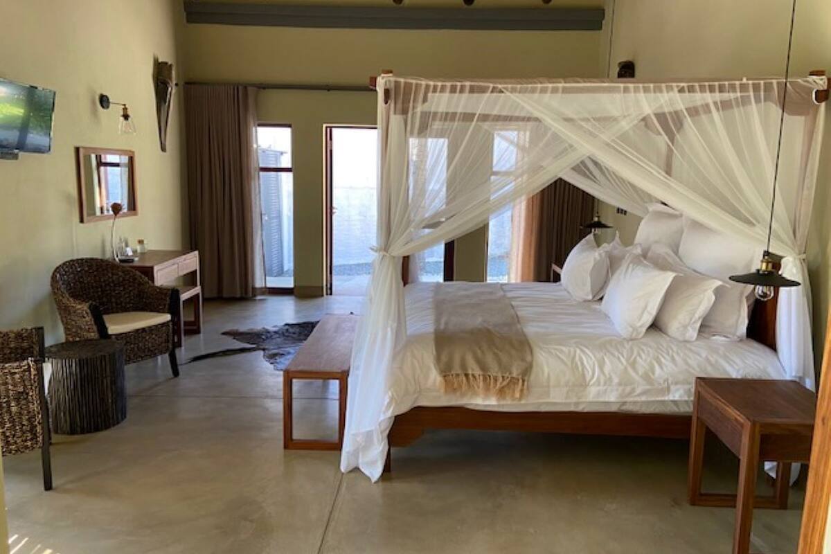 Un'ampia camera da letto con un letto grande, un comodino in legno, una sedia e una scrivania.
