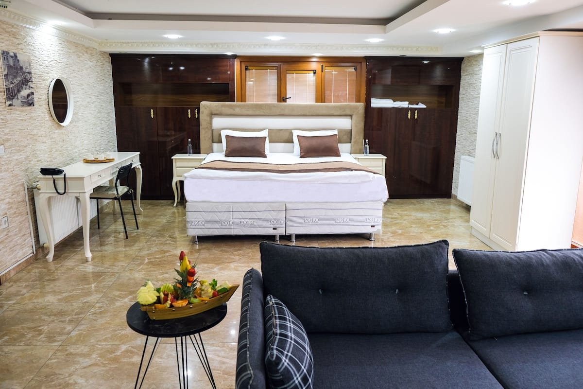 A bedroom with a bed, a desk, a chair, a sofa, and a wardrobe.