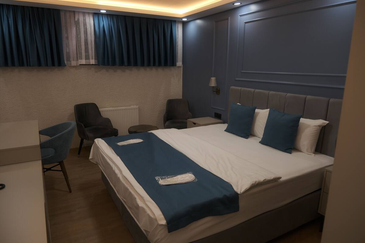 A hotel room with a large bed, a desk, two chairs, and a nightstand.