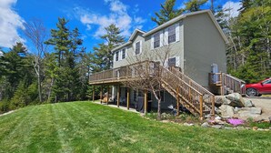 A two-story house with a covered porch and a wooden staircase leading to the second floor. - A spacious sanctuary with 10+ private acres a few miles from Acadia NP entrance (Bar Harbor)