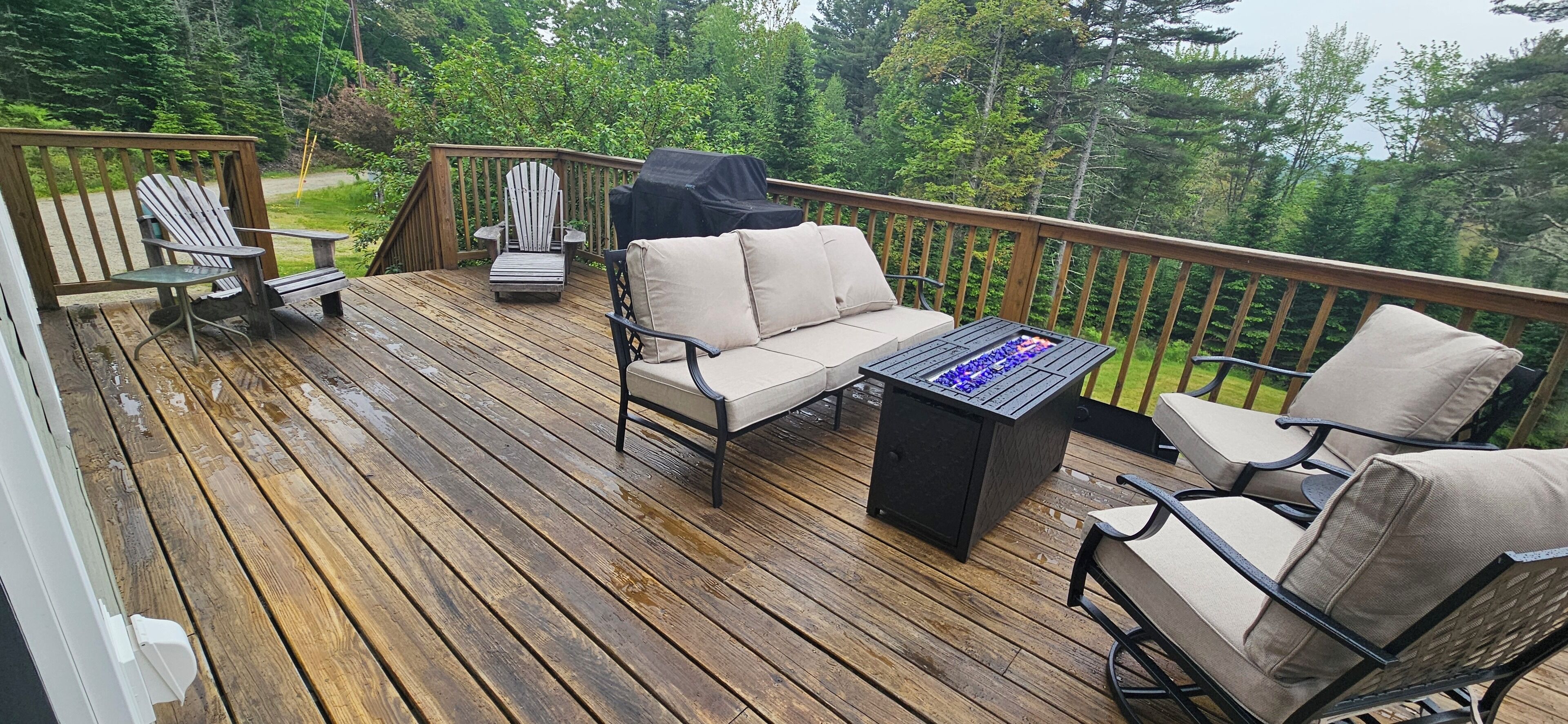 A wooden deck with outdoor furniture including a sofa, chairs, and a table.