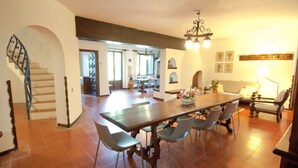 Ein geräumiger Essbereich mit einem großen Holztisch und modernen Stühlen, eine Treppe mit dekorativer Geländer und eine gemütliche Sitzecke mit Sofa und Lampe.
