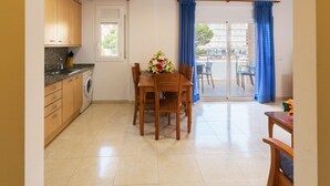 A compact kitchen with a dining area and a balcony with blue curtains.