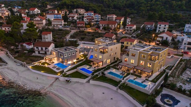 Zona residencial costera con edificios modernos de varios pisos, una playa y una piscina.