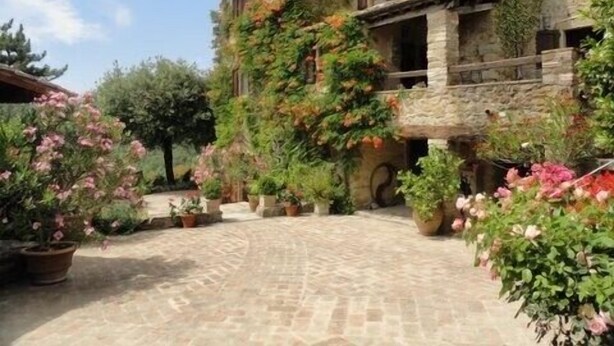 Un edificio de piedra con un patio rodeado de macetas con plantas y flores.