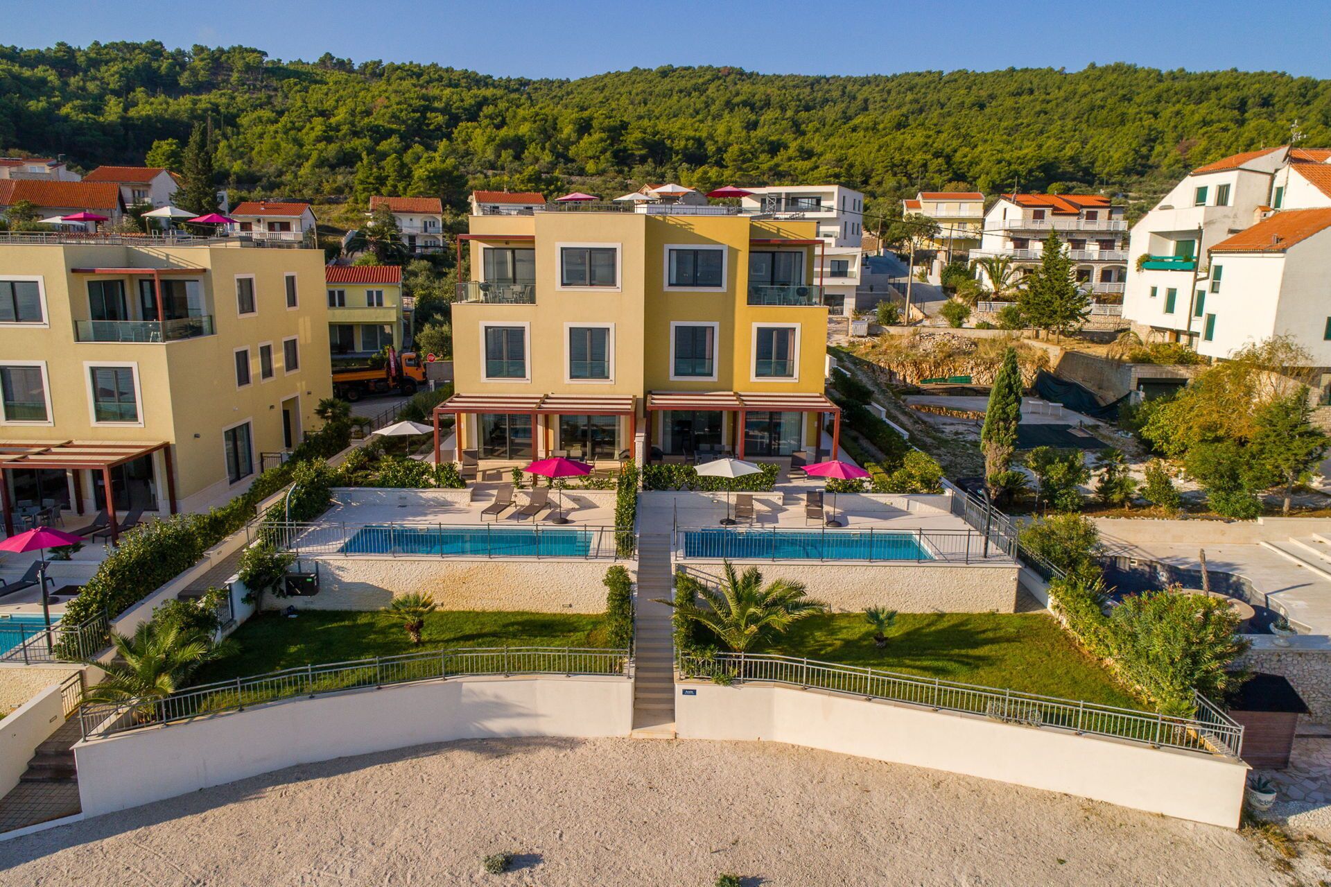 A resort with multiple buildings, outdoor pools, and a mountainous backdrop.