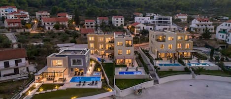 A modern residential complex with multiple buildings, a swimming pool, and a landscaped garden.