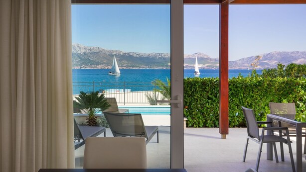 A balcony with a view of the sea, a pool, and a table with chairs. - Beachfront Villa Lemonade with Pool III (Trogir)