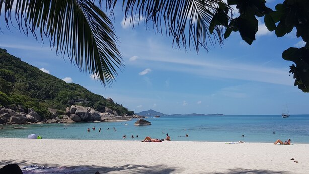 A beach with clear turquoise water, people sunbathing, and a sailboat in the distance. - Villa Paradise with pool and sea view (Ko Samui)