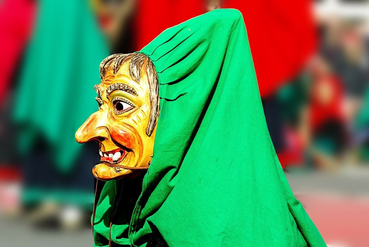 A person wearing a green garment with a mask.