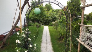 A garden pathway with a metal archway, surrounded by greenery and potted plants. - 77qm 4Pers SatTV Garden Bed linen Towels Final cleaning Parking Washing machine  (Weissensberg)