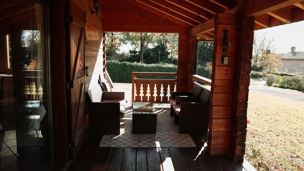 Een houten veranda met zitplaatsen, uitzicht op de tuin en een brievenbus.