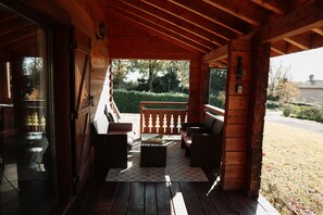 A wooden porch with outdoor seating, a view of the garden, and a mailbox.