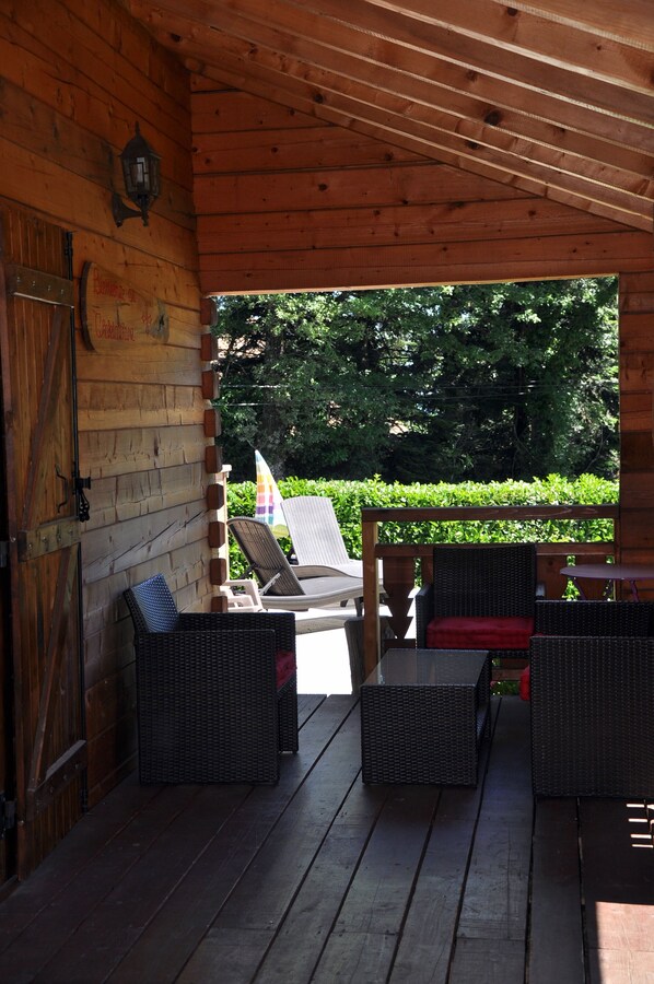 A covered porch with wicker furniture and a view of a garden.