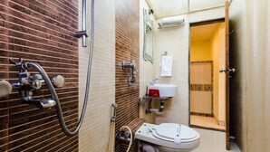 A bathroom with a shower, toilet, sink, and a mirror. - Hotel Arma (Mumbai)