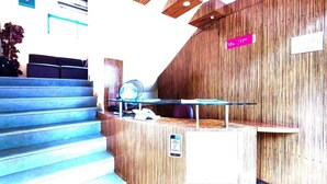 A reception desk with a wooden finish, a glass partition, and a sign indicating a 12m/11m height limit. - Hotel Arma (Mumbai)