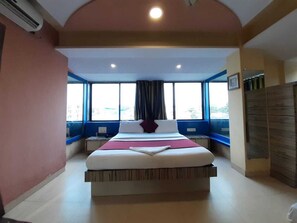 Une chambre avec un grand lit, une fenêtre avec des rideaux et un ventilateur de plafond.
