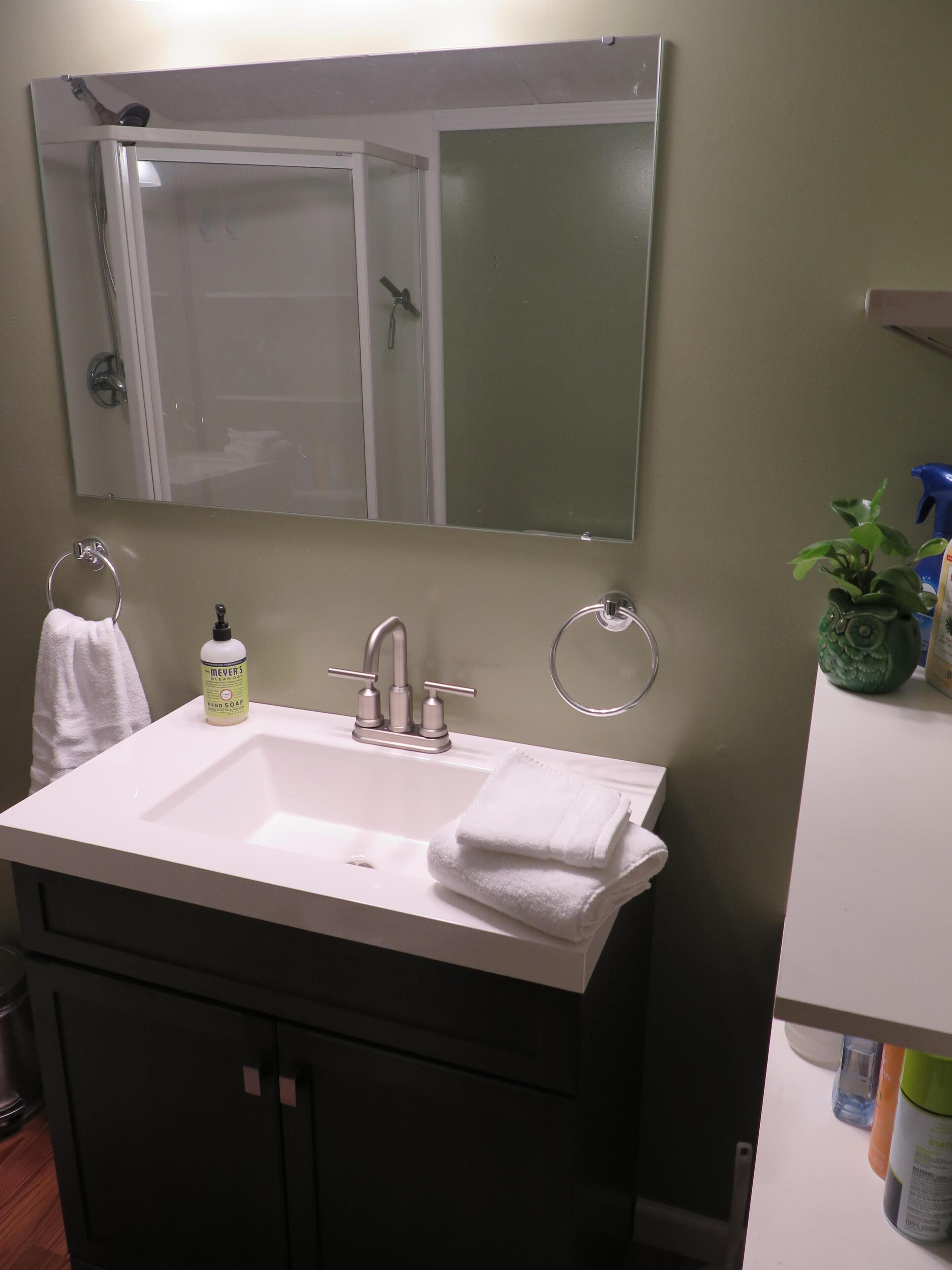 Une salle de bain avec un lavabo blanc, un miroir au-dessus et un porte-serviettes.