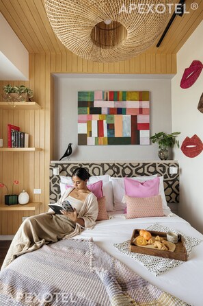 A cozy bedroom with a large bed, a reading area, and a breakfast tray. - Padgett Place - Deluxe Suites (Cebu City)