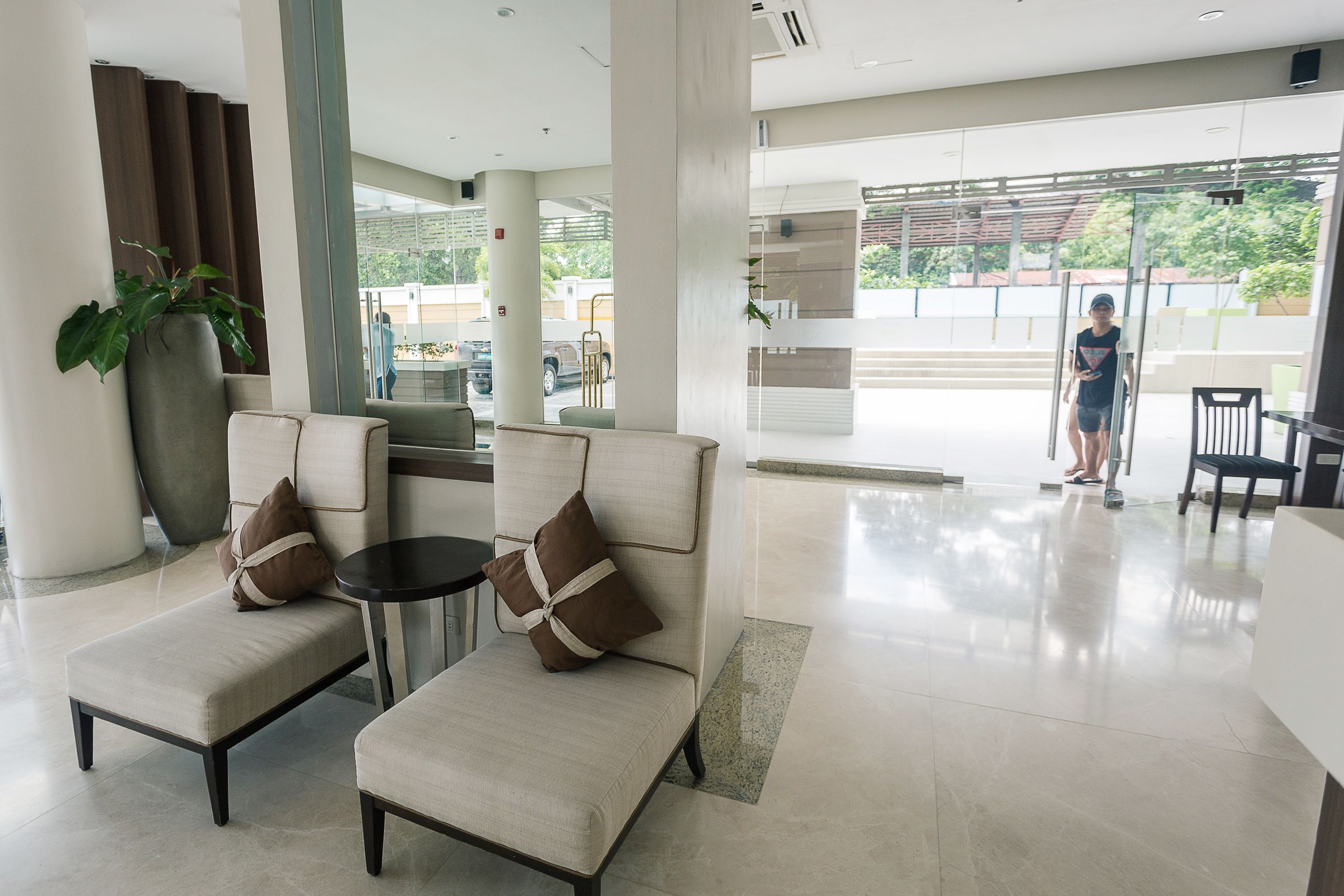 A modern lobby with two sofas, a coffee table, and a large potted plant.