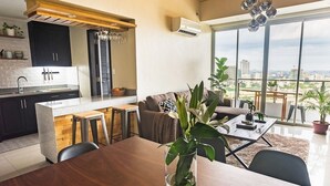 A modern apartment with a kitchen, dining area, and a balcony with a city view. - Padgett Place - Deluxe Suites (Cebu City)