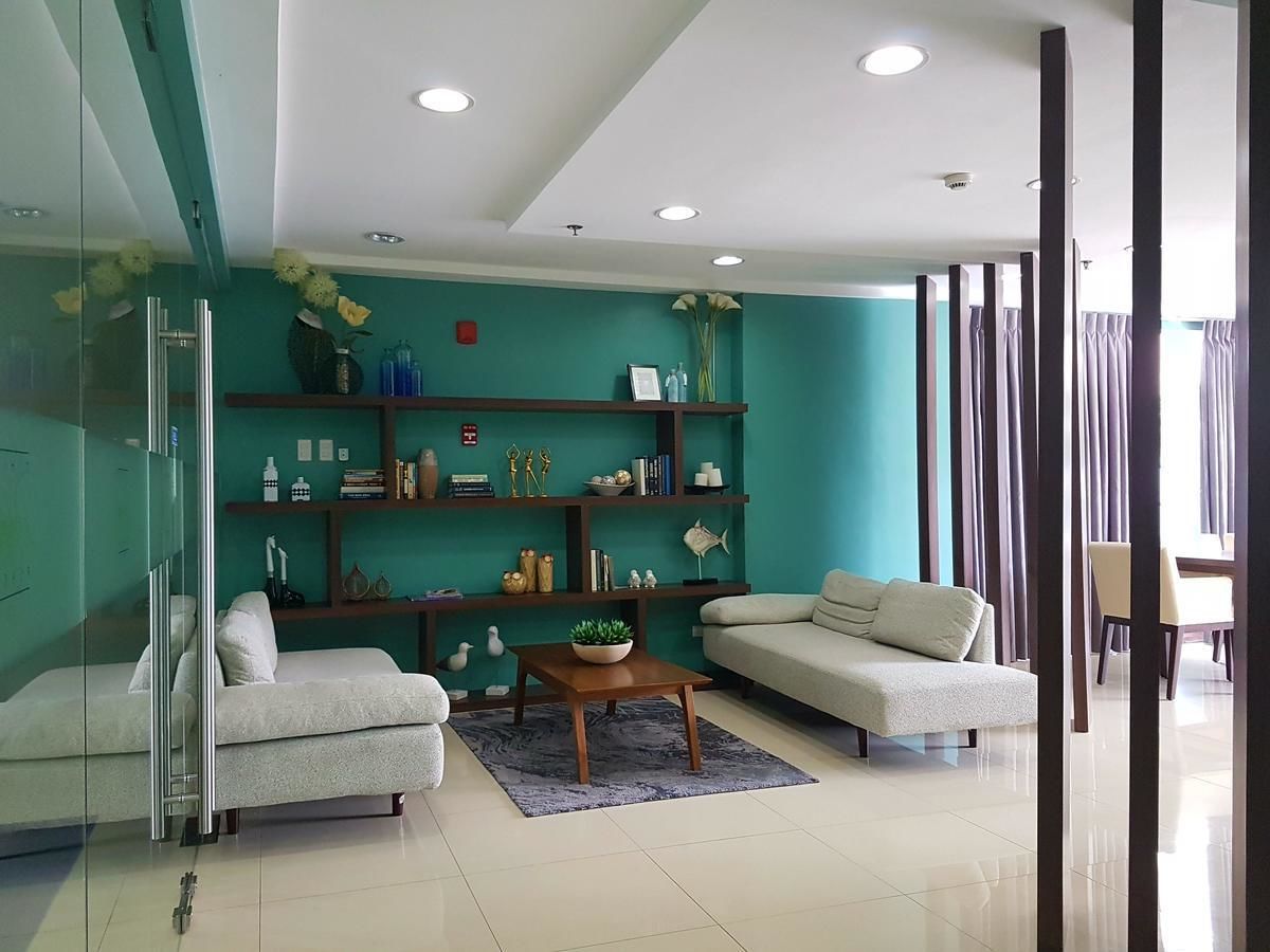 Una sala moderna con una pared de acento color turquesa, cerramiento de ducha de vidrio y un área de comedor con mesa y sillas.