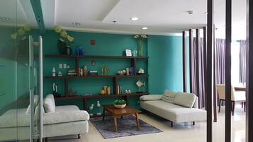 Una sala moderna con una pared de acento color turquesa, cerramiento de ducha de vidrio y un área de comedor con mesa y sillas.
