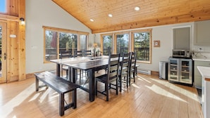 A spacious kitchen with wooden cabinets, a dining area with a large table and chairs, and large windows providing natural light. - Spectacular Peak 7 Open and Great Views! STR21-01365 (Breckenridge)