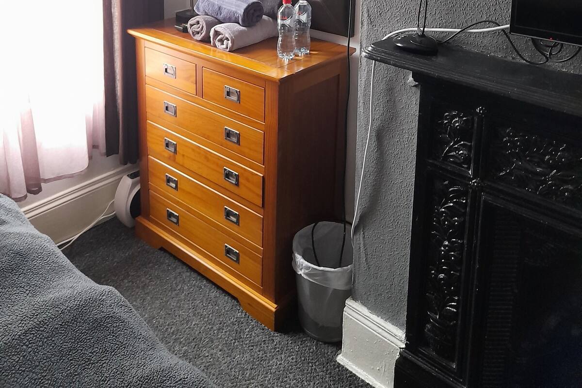 Une chambre d’hôtel avec une commode en bois, un miroir, une télévision et une cheminée.