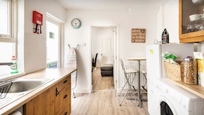 A kitchen with a sink, a fire blanket, a clock, a coffee sign, and a washing machine. - EuroVilla (Belfast)