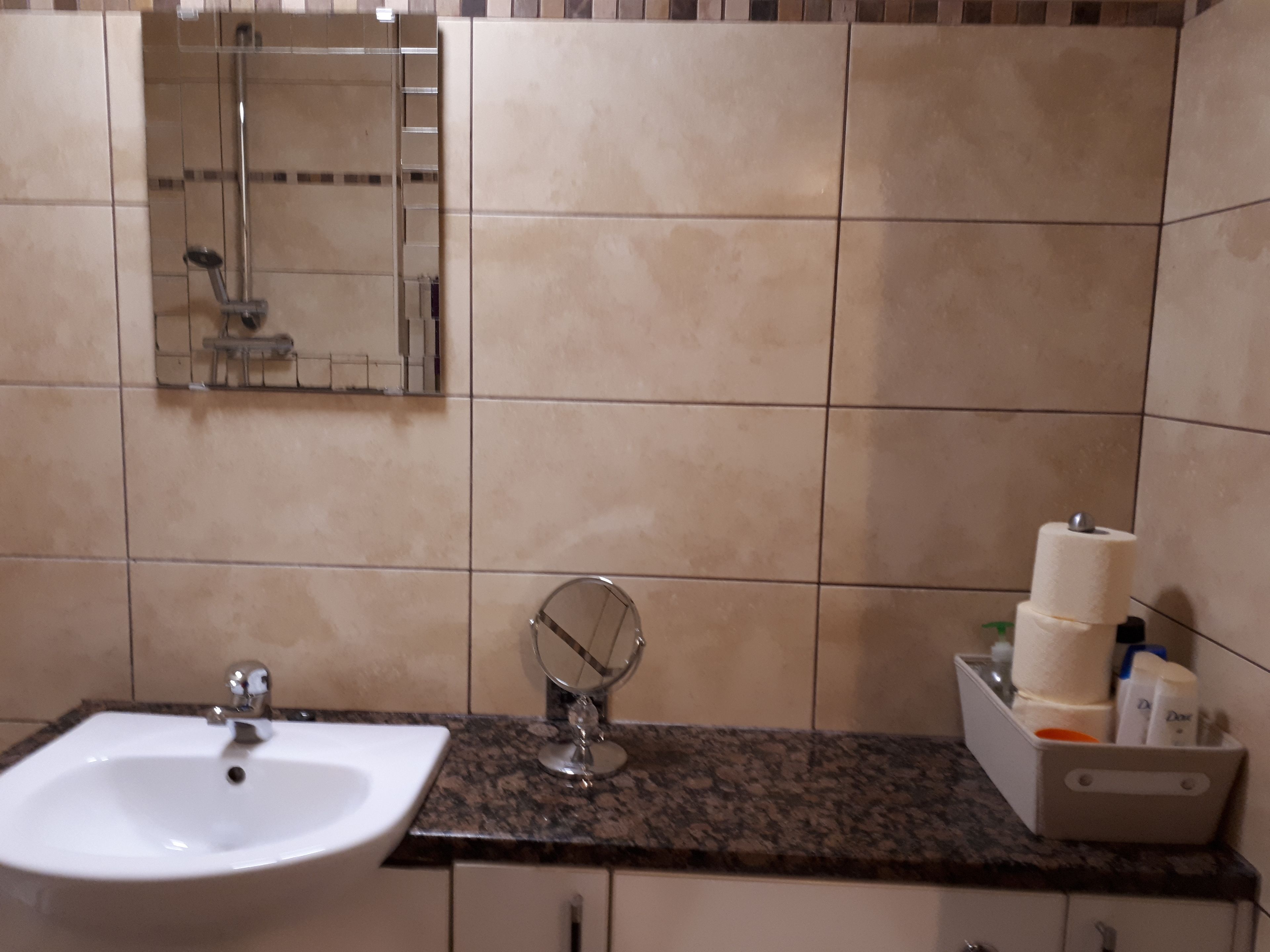 A bathroom with a sink, mirror, and toiletries on the counter.