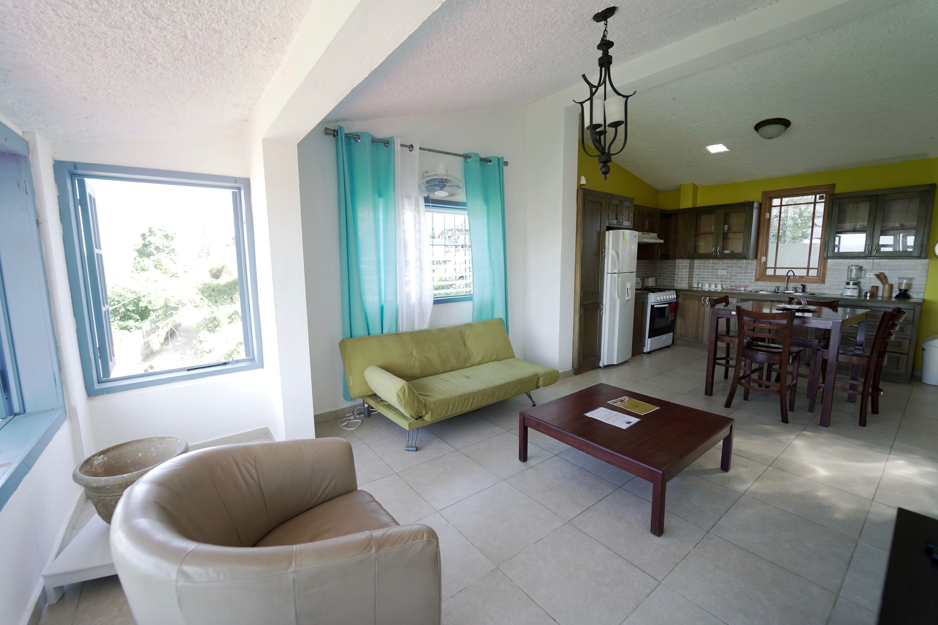 A living room with a sofa, a coffee table, and a dining area with chairs and a table.