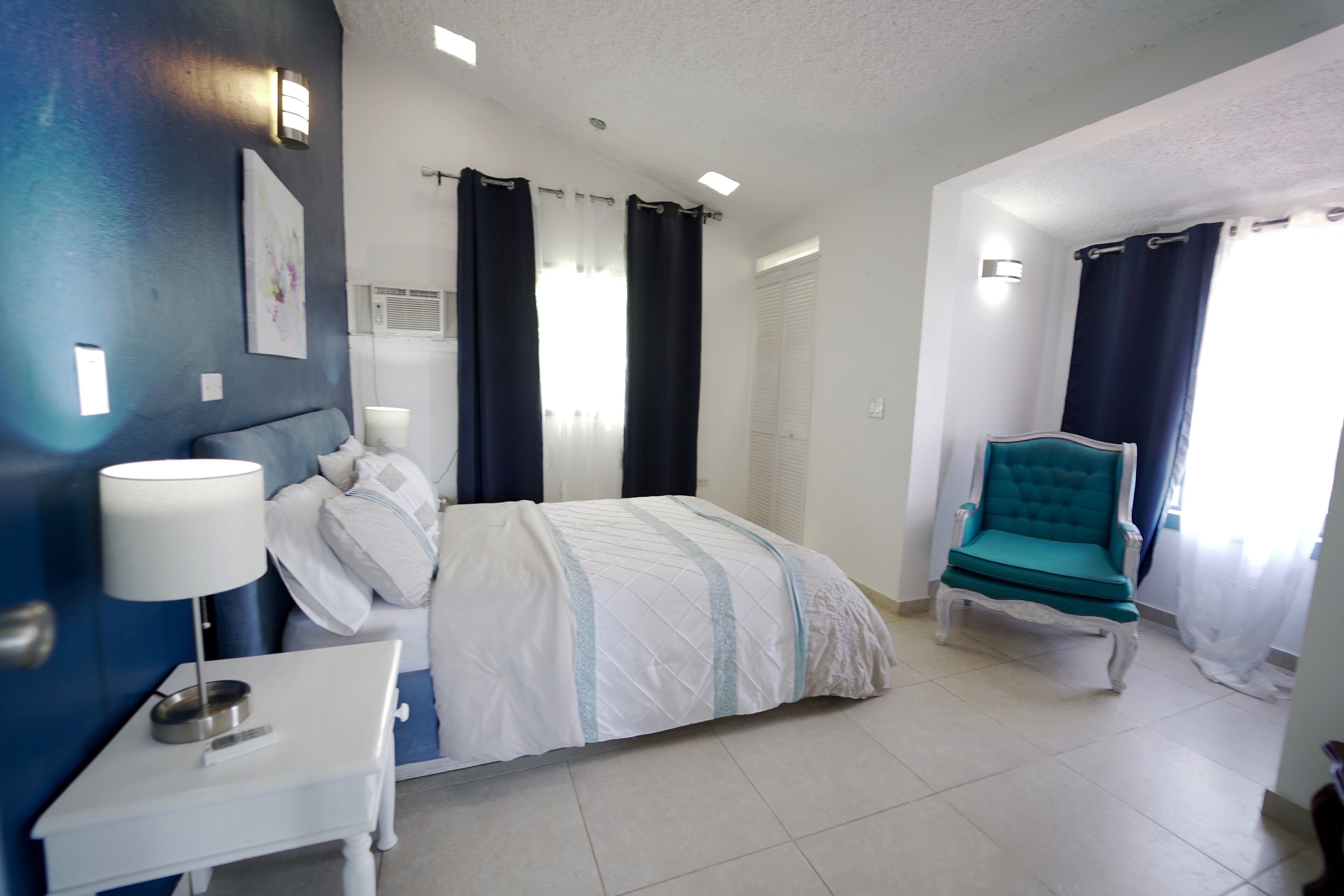 A hotel room with a bed, a nightstand, a chair, and a window with curtains.