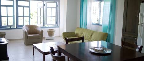 Een eetgedeelte met een houten tafel en stoelen, een bank en een fauteuil.