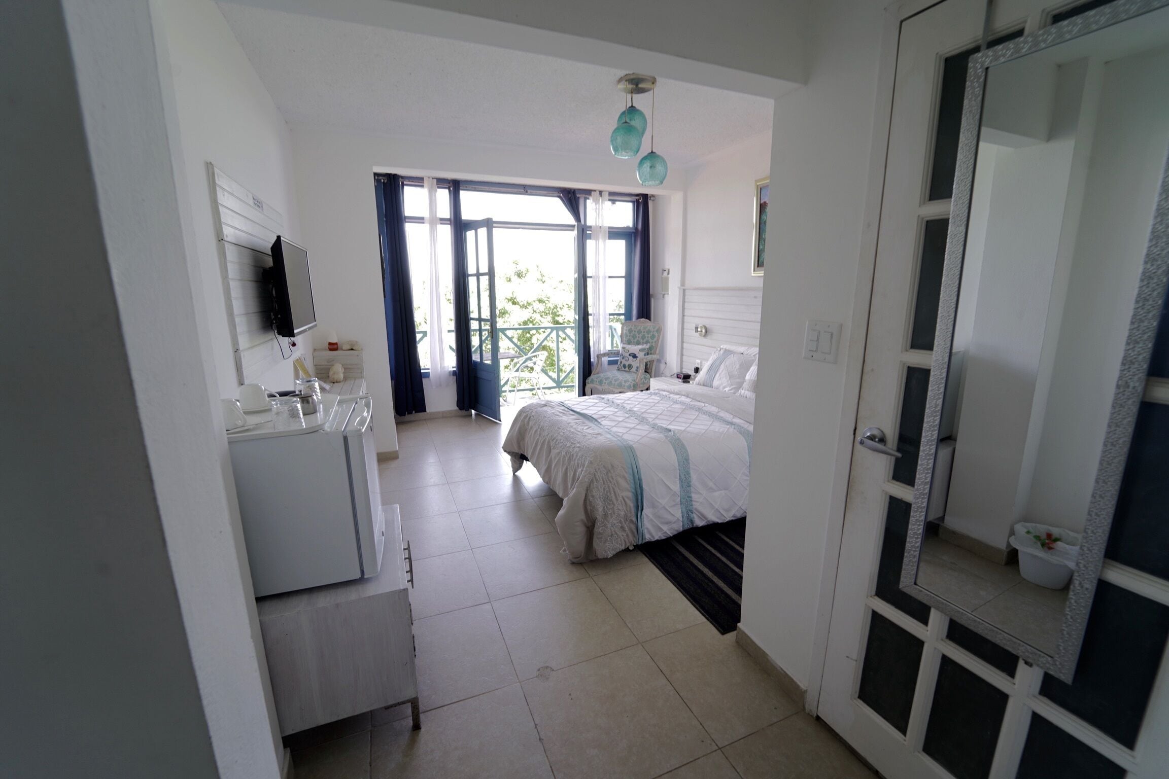 Ein Schlafzimmer mit Bett, Kommode, Spiegel und einem Fenster mit Vorhängen.