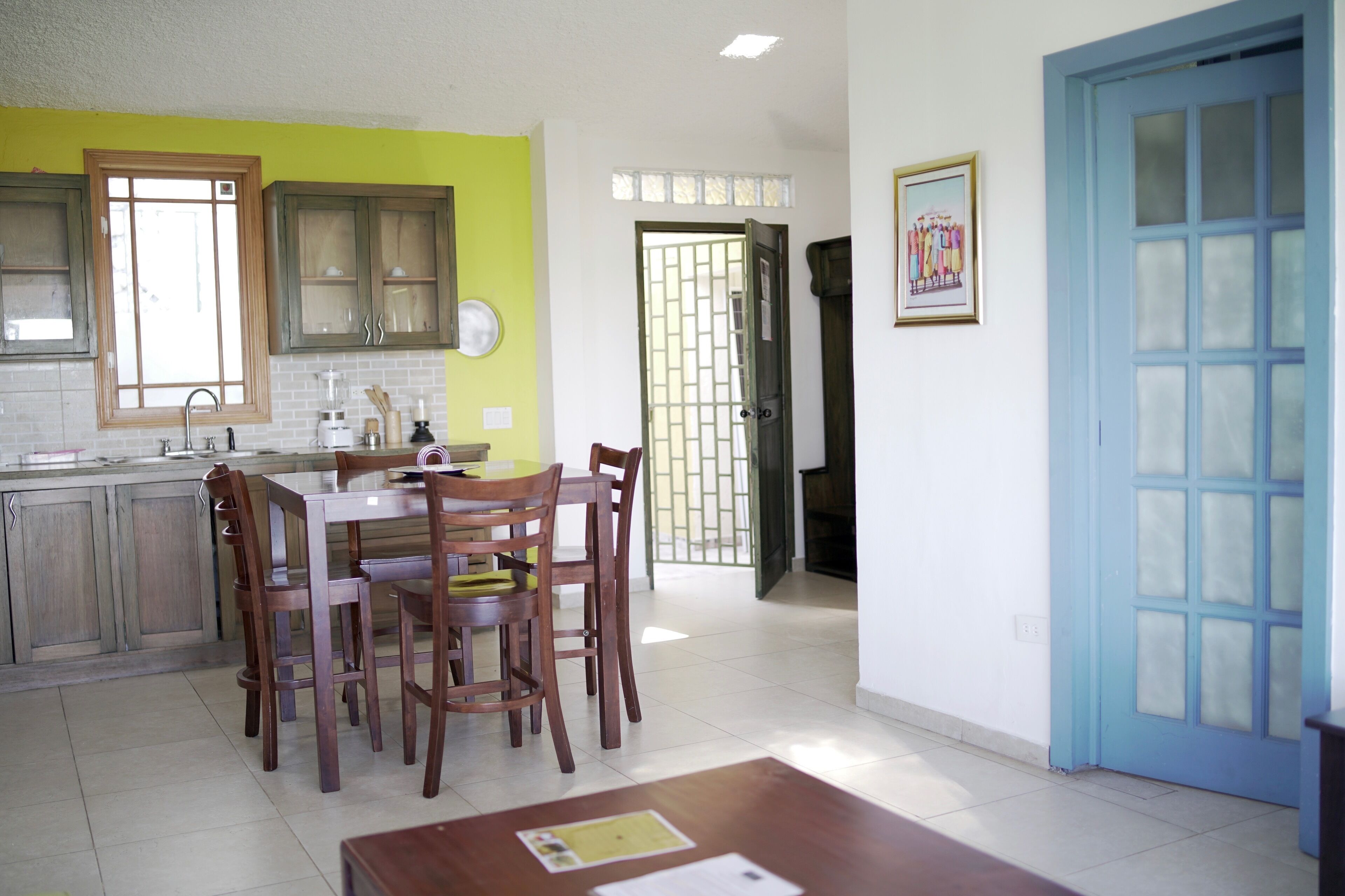 A kitchen with wooden cabinets, a dining table with chairs, and a blue door.