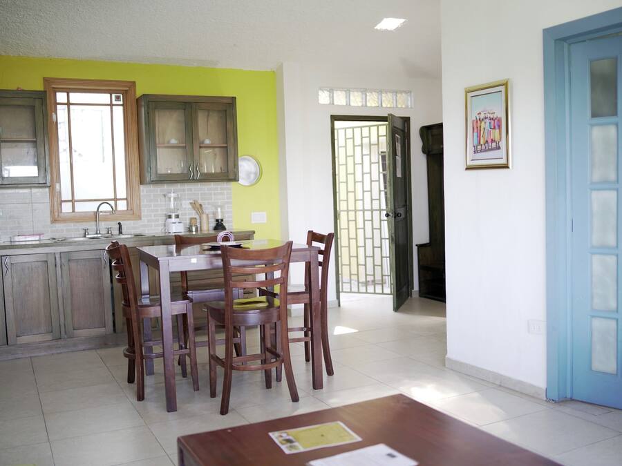 A kitchen with wooden cabinets, a dining table with chairs, and a blue door.