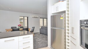 Een moderne keuken met witte kasten, een roestvrijstalen koelkast en een inbouwoven.