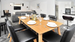 Een moderne eetruimte met een houten tafel voor zes personen, omringd door zwarte lederen stoelen.