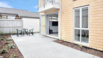 A residential building with a balcony, a patio with outdoor furniture, and a brick exterior.