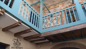 A balcony with blue railings and a decorative ceiling mural. - Nao Victoria Hostel (Cusco)