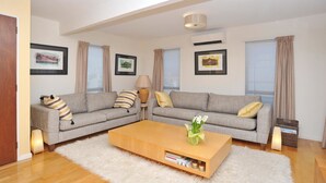 A modern living room with two grey sofas, a wooden coffee table, and a white shag rug.