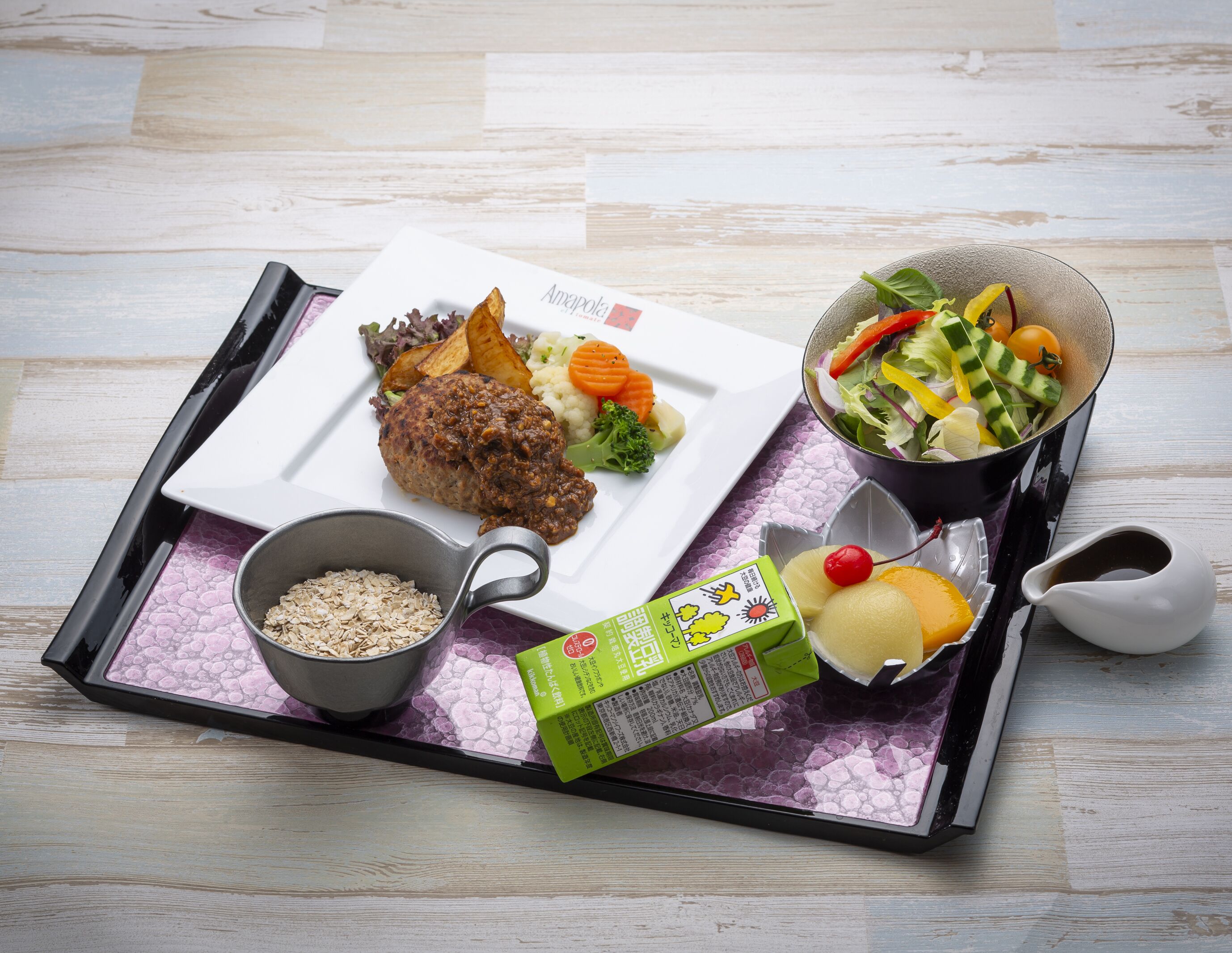 A tray with a meal consisting of meat, vegetables, and a side dish, along with a bowl of grains and a carton of milk.