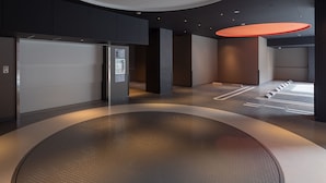 Un intérieur moderne avec un espace salon circulaire, un comptoir d’accueil et une grande enseigne lumineuse.