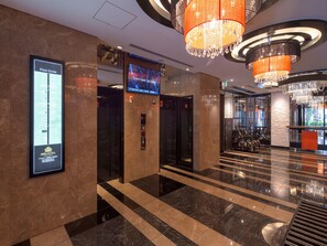 A hotel lobby with a floor guide, elevators, and a reception area.