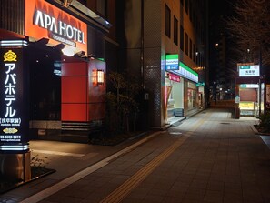 A hotel named APA HOTEL with a prominent sign, a FamilyMart store, and a visible entrance.