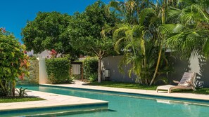 Une piscine à l’eau d’un bleu cristallin, entourée d’une végétation luxuriante et de palmiers.